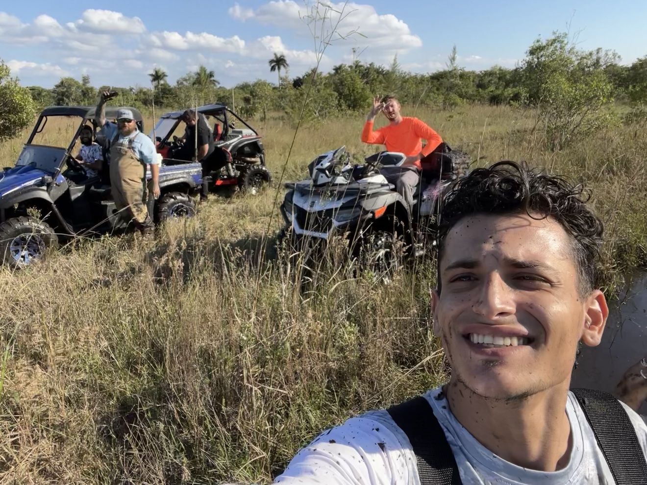 Group selfie of riders with ATVs in a field