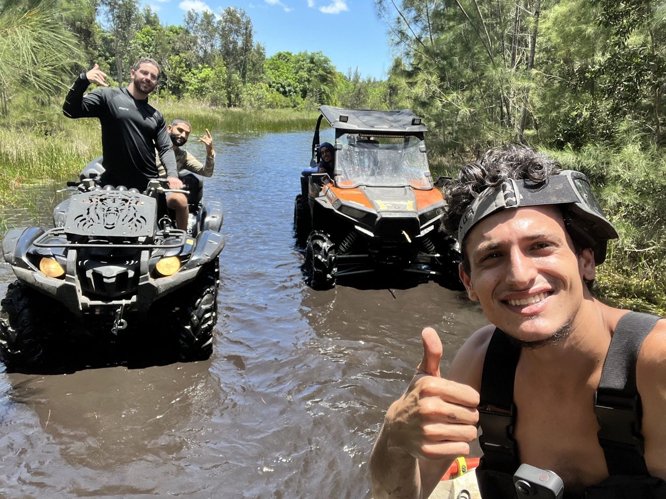 Riders in a water trail with ATVs